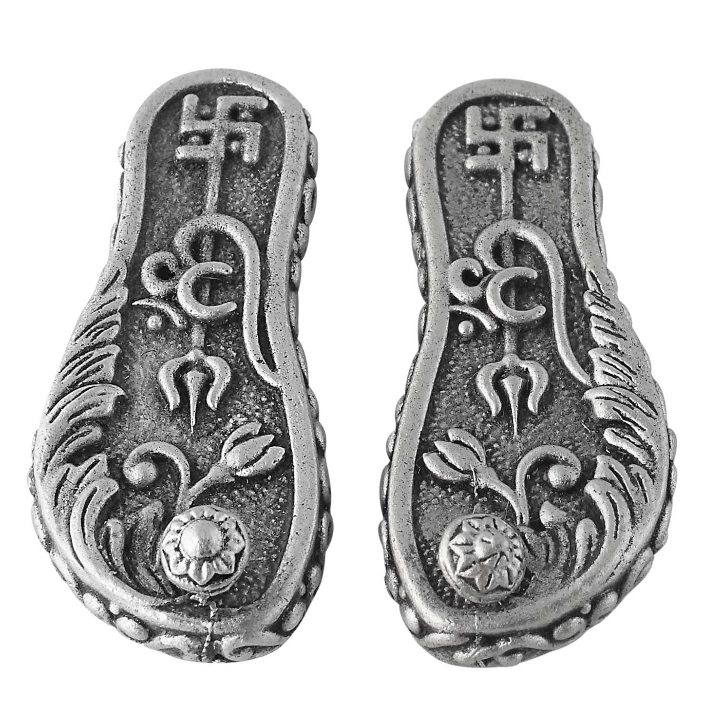 Pair of silver caharan paduka with intricate designs on a white background