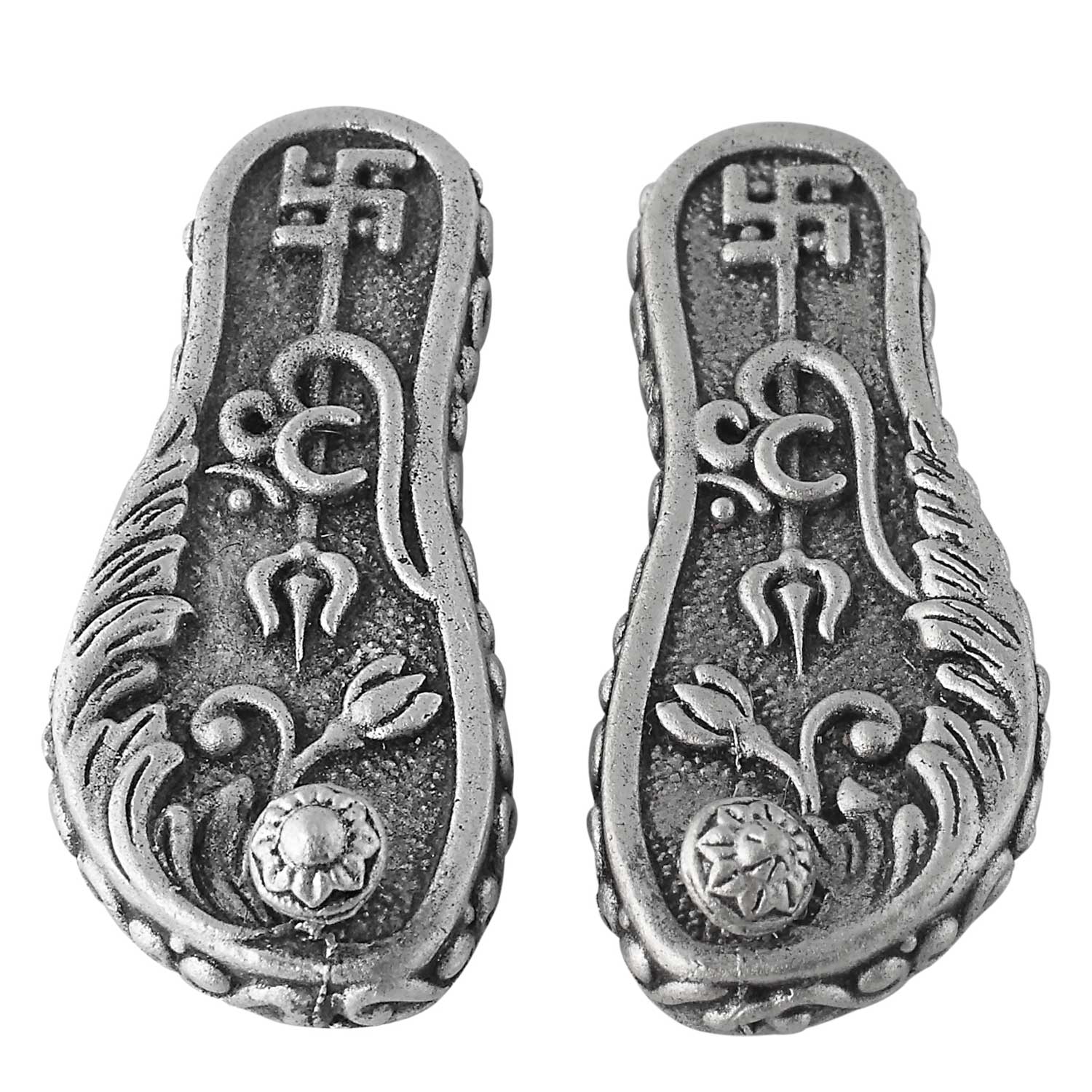 Pair of silver caharan paduka with intricate designs on a white background
