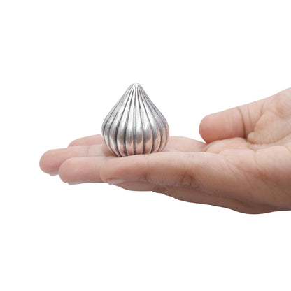 Silver modak held in a hand on a white background
